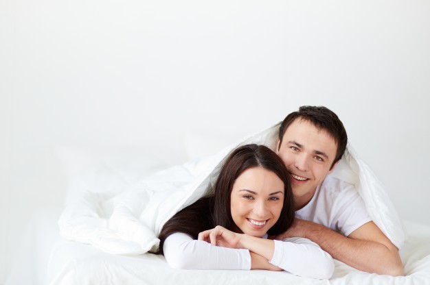 sourire-couple-allonge-dans-son-lit_1098-3788